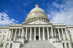 US Capitol building viewed from the ground, with blue sky and clouds behind.